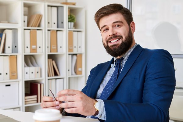 smiling-businessman-posing-at-desk-in-office-JTBMSTT.jpg